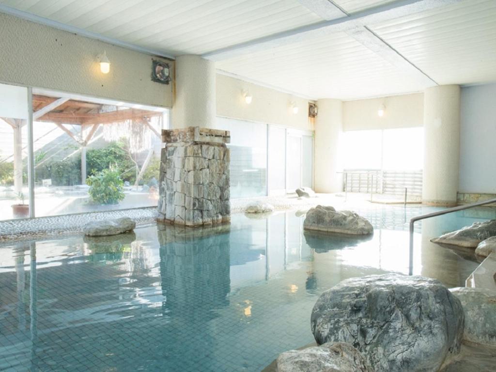 un grand bassin d'eau avec des rochers dans un bâtiment dans l'établissement Nangoku Hotel, à Minamiboso