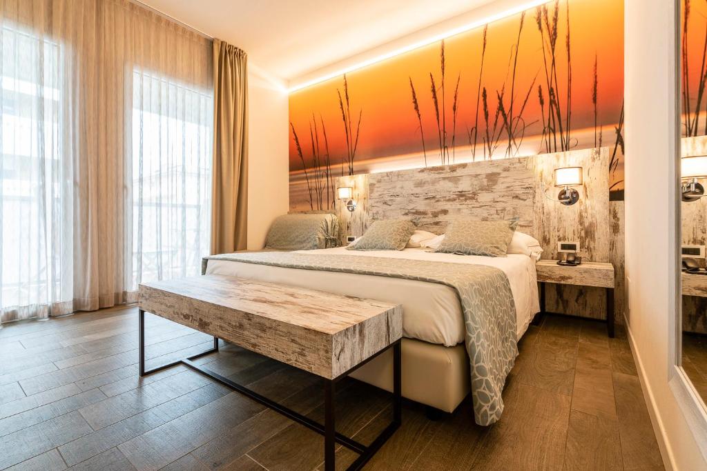 une chambre avec un grand lit et une table dans l'établissement Hotel Ambassador, à Bibione