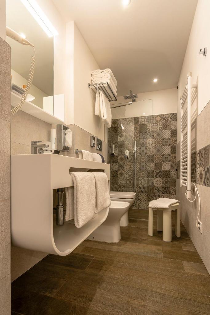 une salle de bain avec un lavabo, des toilettes et une douche dans l'établissement Hotel Ambassador, à Bibione