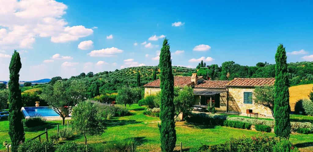 une maison dans un jardin avec des arbres au premier plan dans l'établissement Villa S.Anna, à Montisi