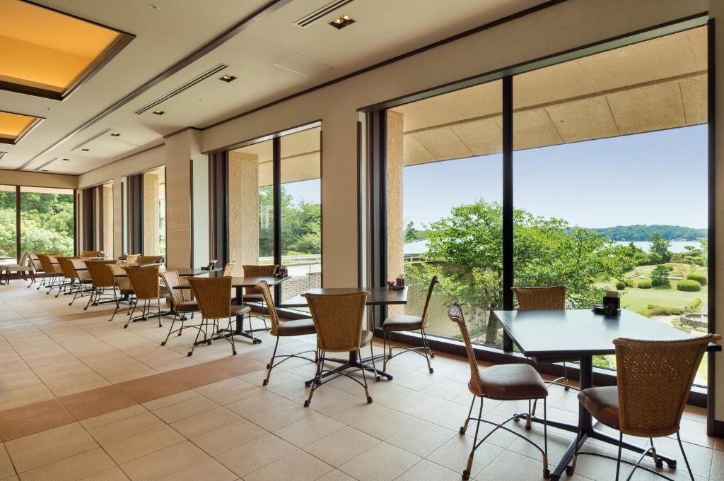 une salle à manger avec tables et chaises et de grandes fenêtres dans l'établissement Kashikojima Hojoen, à Shima