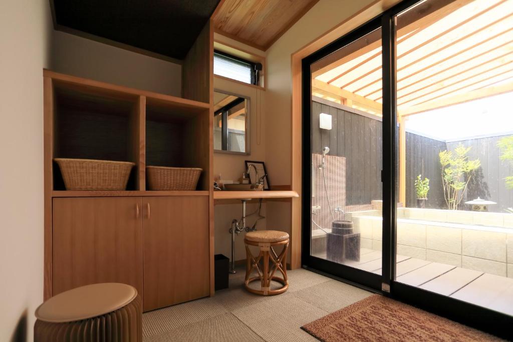 La salle de bains est pourvue d'une porte en verre menant à une baignoire. dans l'établissement Jinpuso, à Miyazu