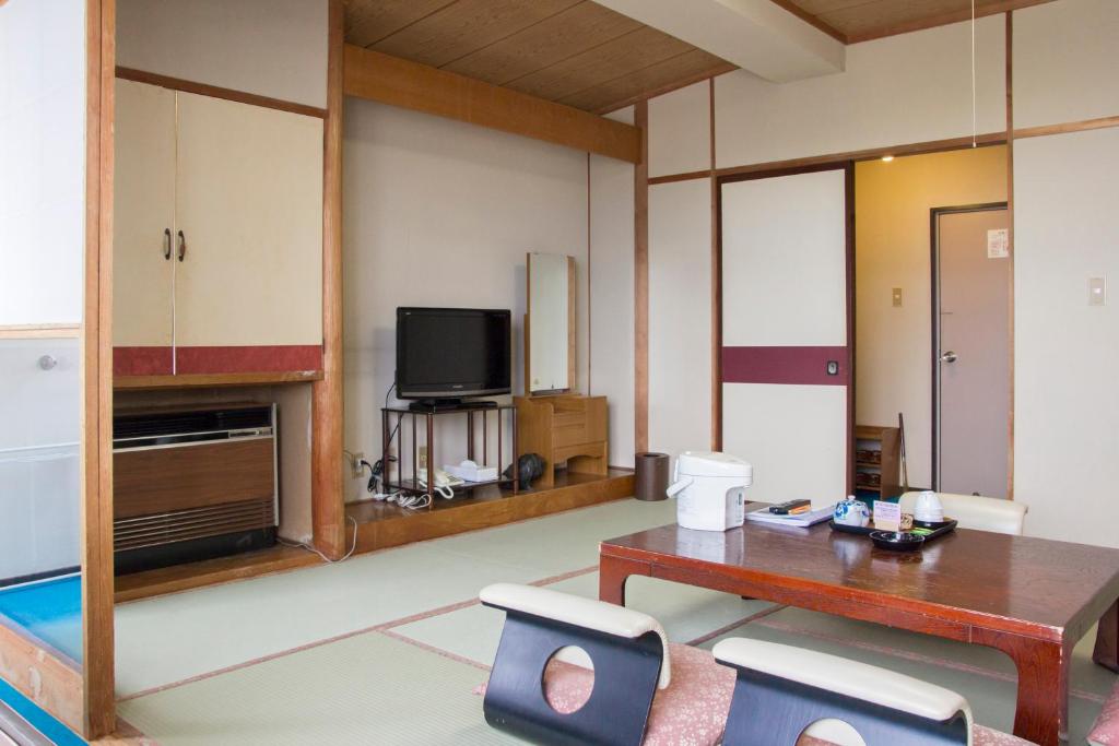 un salon avec une table et une télévision dans l'établissement Lake Side Hotel Minatoya, à Inawashiro