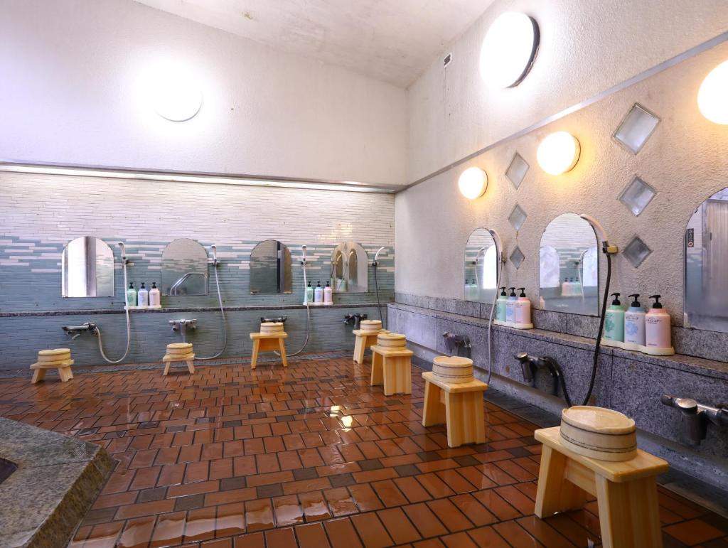 La salle de bains est pourvue de lavabos, de miroirs et de bancs. dans l'établissement Besshoonsen Nanjyo Ryokan, à Ueda