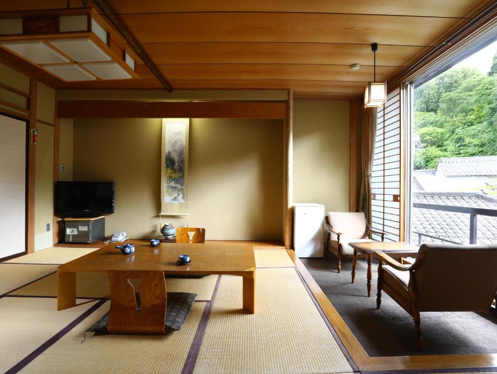 un salon avec une table et une grande fenêtre dans l'établissement Besshoonsen Nanjyo Ryokan, à Ueda