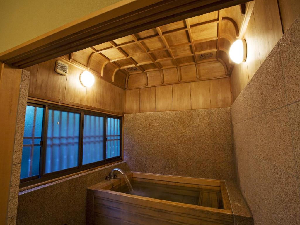 La salle de bains est pourvue d'une baignoire et d'une fenêtre. dans l'établissement Kotohira Kadan, à Kotohira