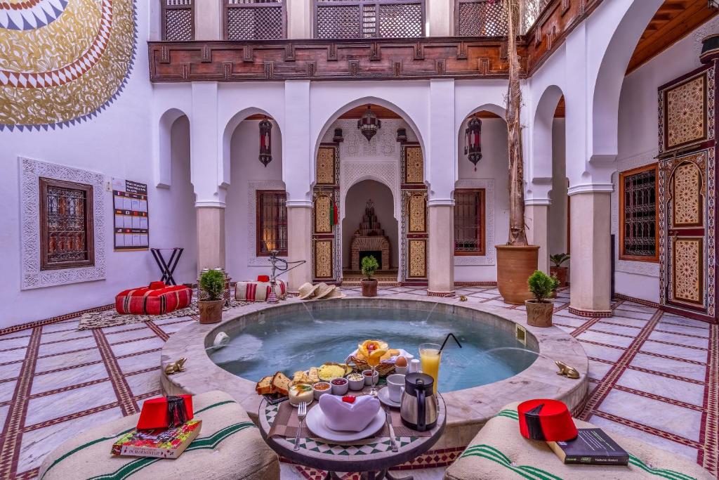 - une piscine dans un bâtiment avec une table et de la nourriture dans l'établissement Riad Safran et Cannelle & Spa, à Marrakech