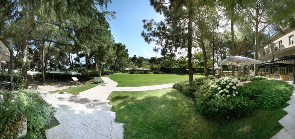 un jardin avec des arbres et une pelouse avec un bâtiment dans l'établissement Villa Maria Hotel & SPA, à Francavilla al Mare