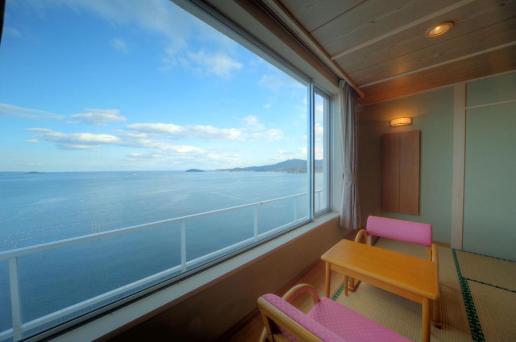 une pièce avec une grande fenêtre avec une table et des chaises dans l'établissement Minami Sanriku Hotel kanyo, à Shizukawa