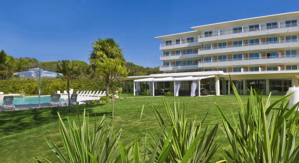 un grand bâtiment avec une pelouse et une piscine dans l'établissement Hotel San Marco, à Bibione