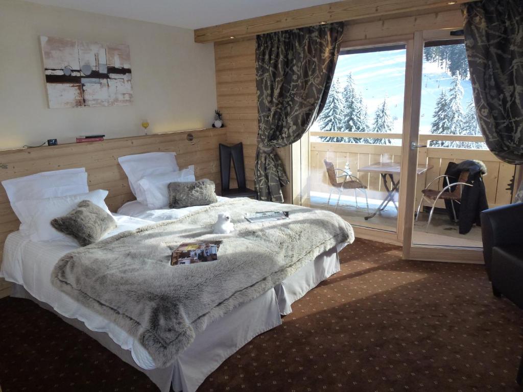 une chambre avec un grand lit et un balcon dans l'établissement Hôtel Restaurant "Les Sapins" Wellness & Gourmet, à Manigod