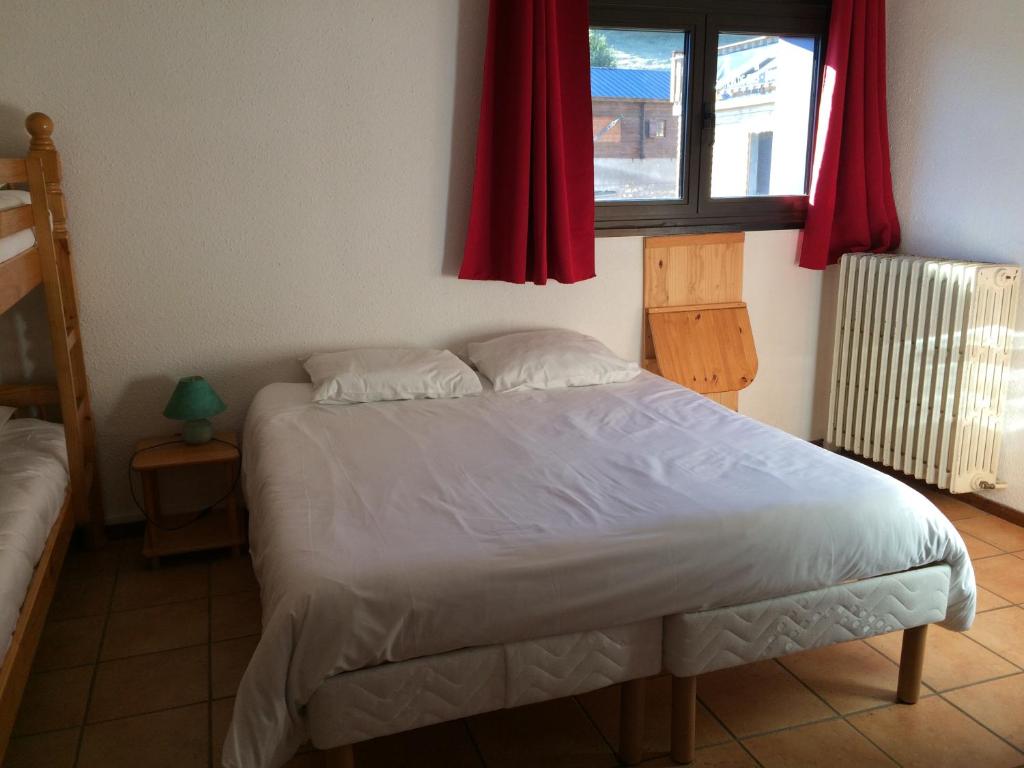 une chambre avec un lit et une fenêtre avec des rideaux rouges dans l'établissement Hôtel Le Tuc de l'Etang, à Boutx