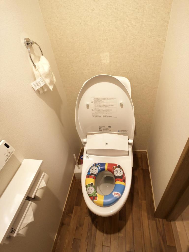 La salle de bains est pourvue de toilettes avec un siège et des autocollants. dans l'établissement Harper House, à Osaka 37 autres photos