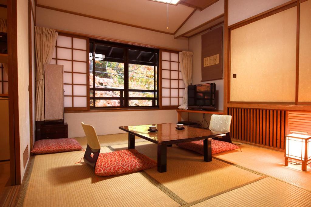 une pièce avec une table, des chaises et une fenêtre dans l'établissement Tsuruya Ryokan, à Karuizawa