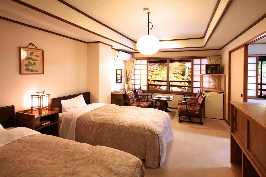 une chambre d'hôtel avec deux lits, une table et des chaises dans l'établissement Tsuruya Ryokan, à Karuizawa