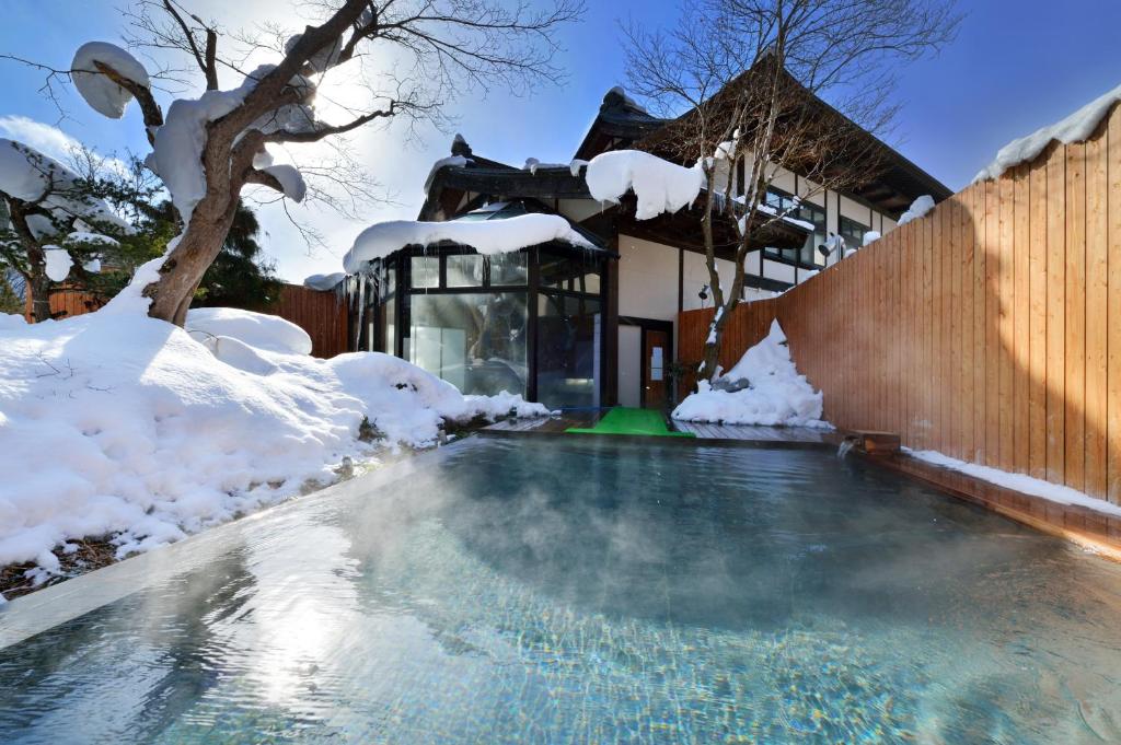 - une piscine couverte de neige à côté d'une maison dans l'établissement Yukaen, à Hanamaki