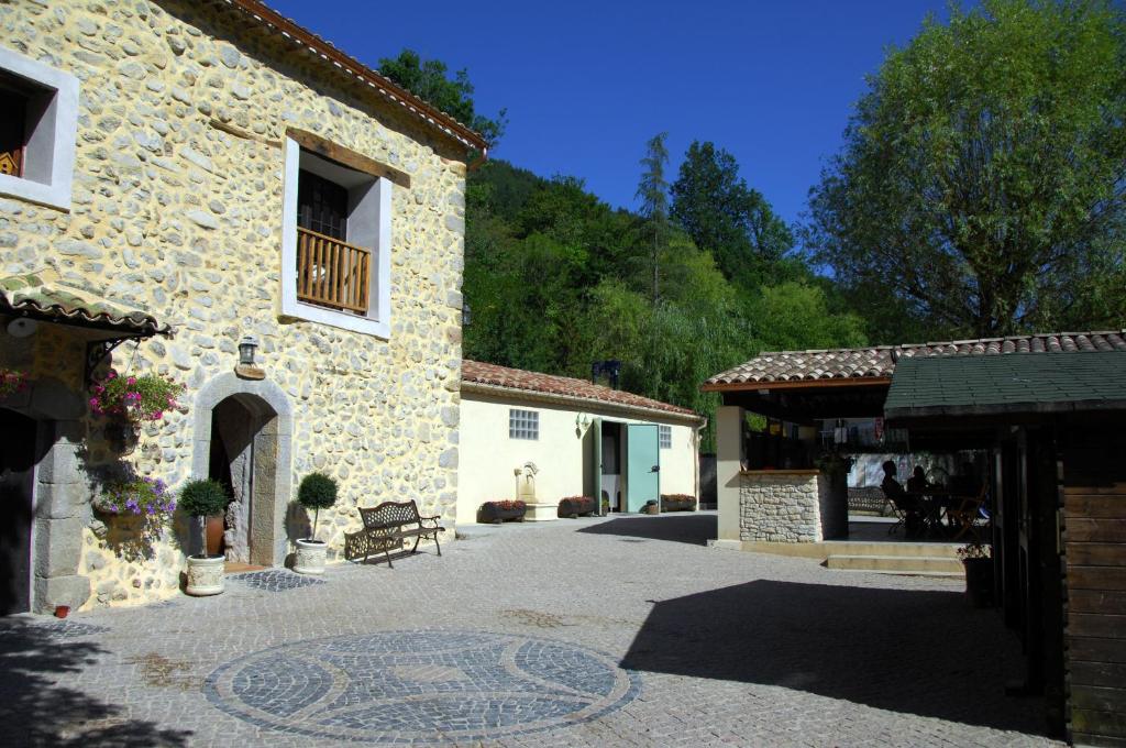 un bâtiment en pierre avec un banc dans une cour dans l'établissement Camping La Ferme de Castellane, à Castellane