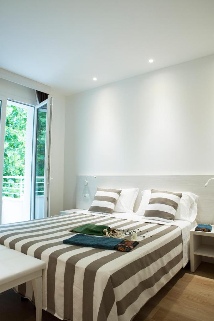 une chambre blanche avec un grand lit avec des draps rayés dans l'établissement Hotel Houston Suites, à Rimini