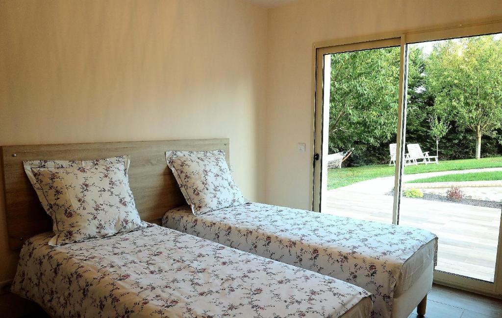 une chambre avec un lit et une grande fenêtre dans l'établissement Gîte Jet d'eau avec piscine intérieure 30 minutes Versailles, à Montainville 28 autres photos