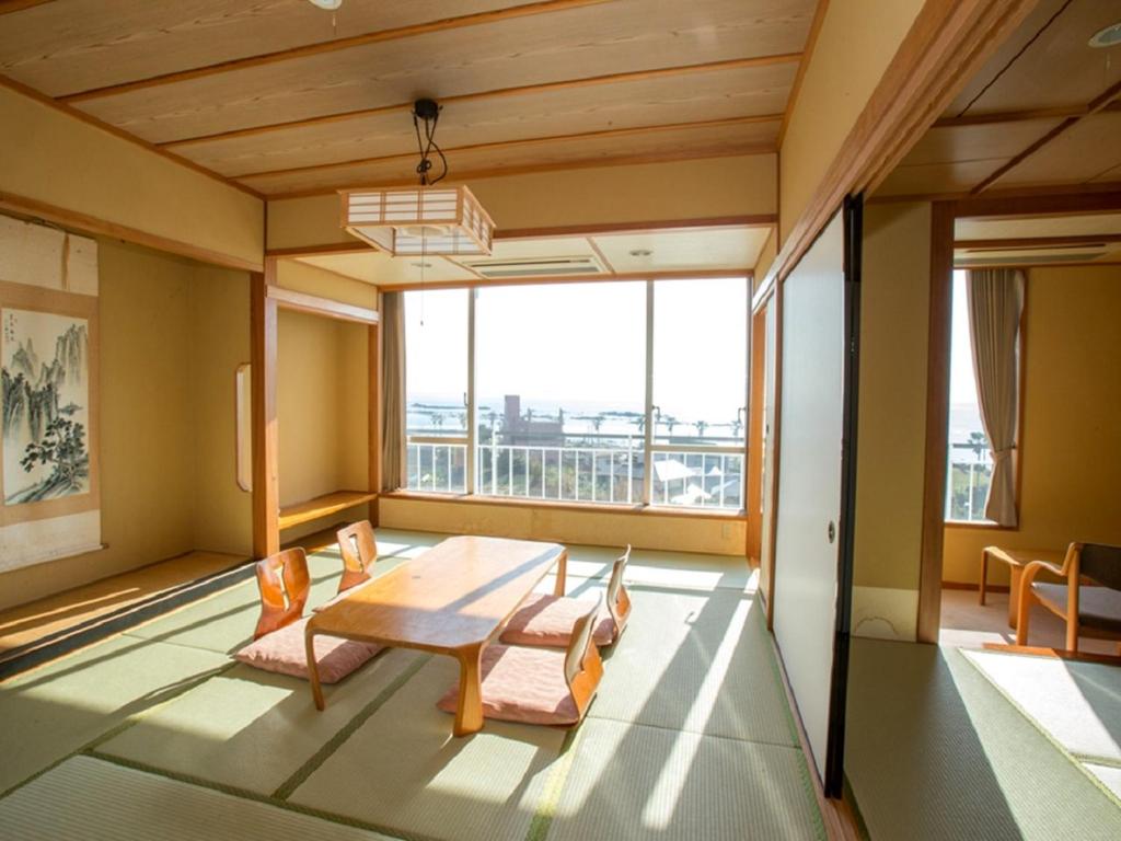 une pièce avec une table et des chaises et une grande fenêtre dans l'établissement Nangoku Hotel, à Minamiboso