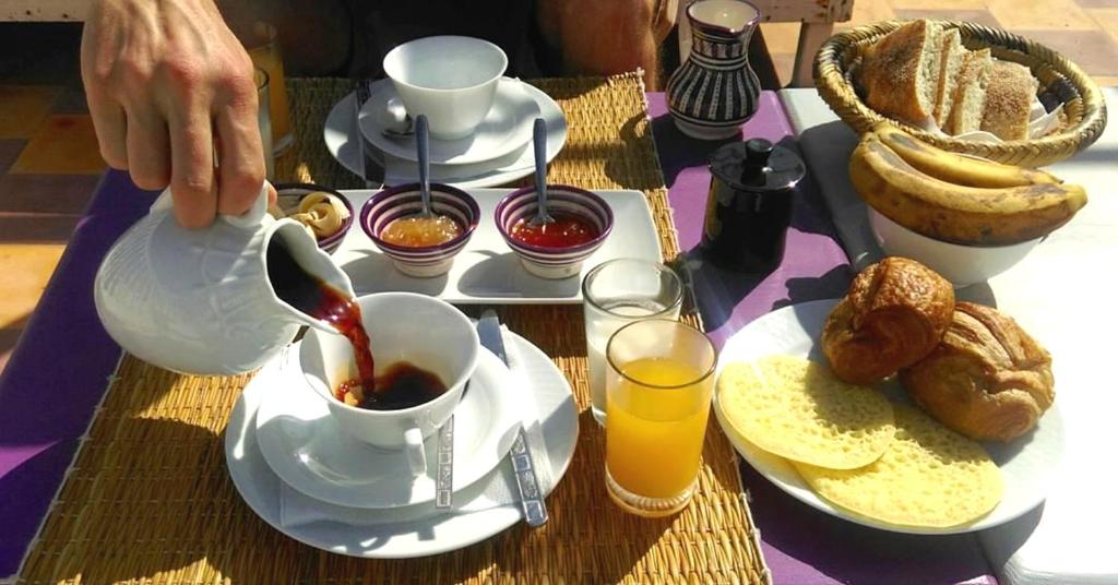 une personne versant du thé dans une tasse sur une table avec de la nourriture dans l'établissement Riad Saltana, à Essaouira