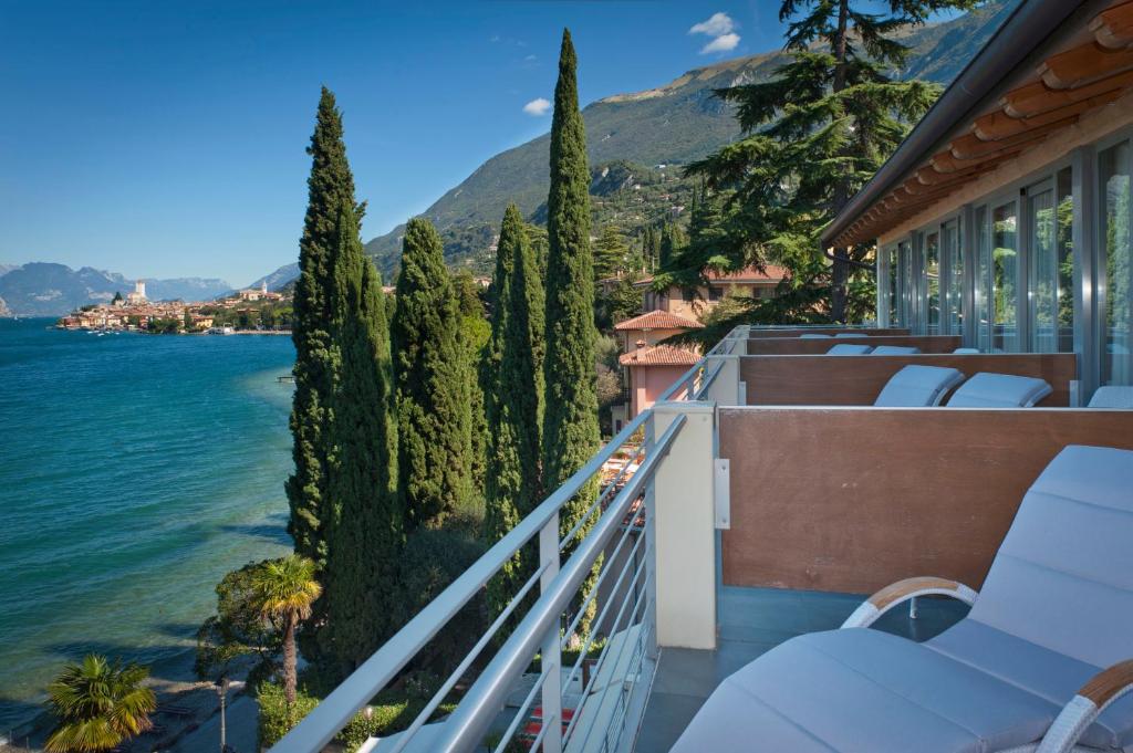 un balcon avec des chaises et une vue sur l'eau dans l'établissement Beach Hotel Du Lac Malcesine, à Malcesine