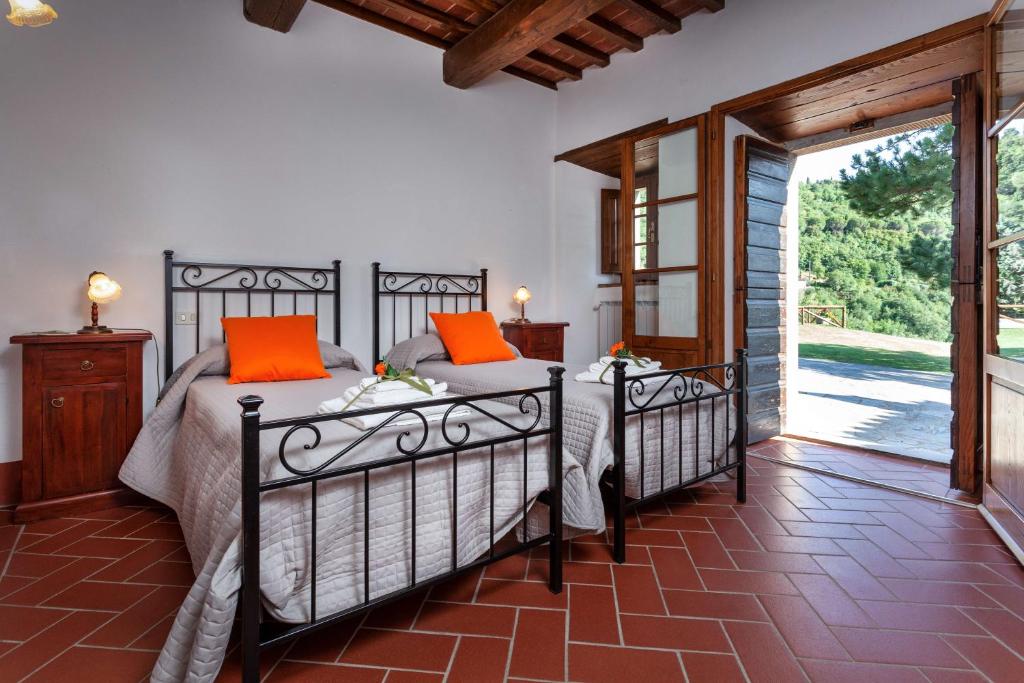 - une chambre avec 2 lits et des oreillers orange dans l'établissement Agriturismo Le Celle, à Cortone