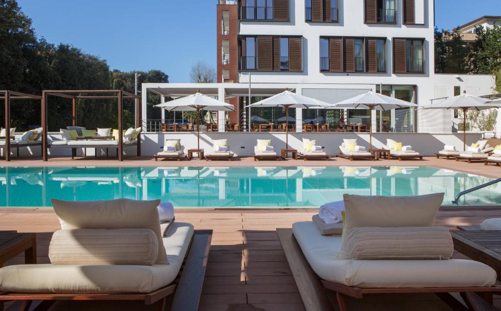 une piscine avec des chaises longues et un hôtel dans l'établissement Principe Forte Dei Marmi - Resort & Spa, à Forte dei Marmi