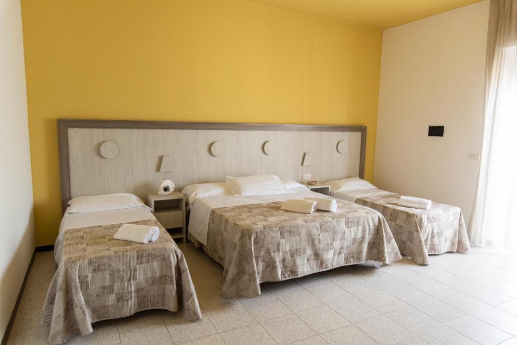 deux lits dans une chambre aux murs jaunes dans l'établissement Hotel Continental, à Tortoreto Lido
