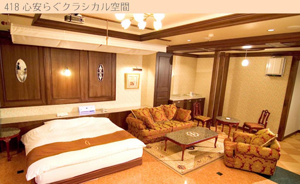 une chambre avec un lit, un canapé et des chaises dans l'établissement Hotel Very Matsusaka (Adult Only), à Matsuzaka