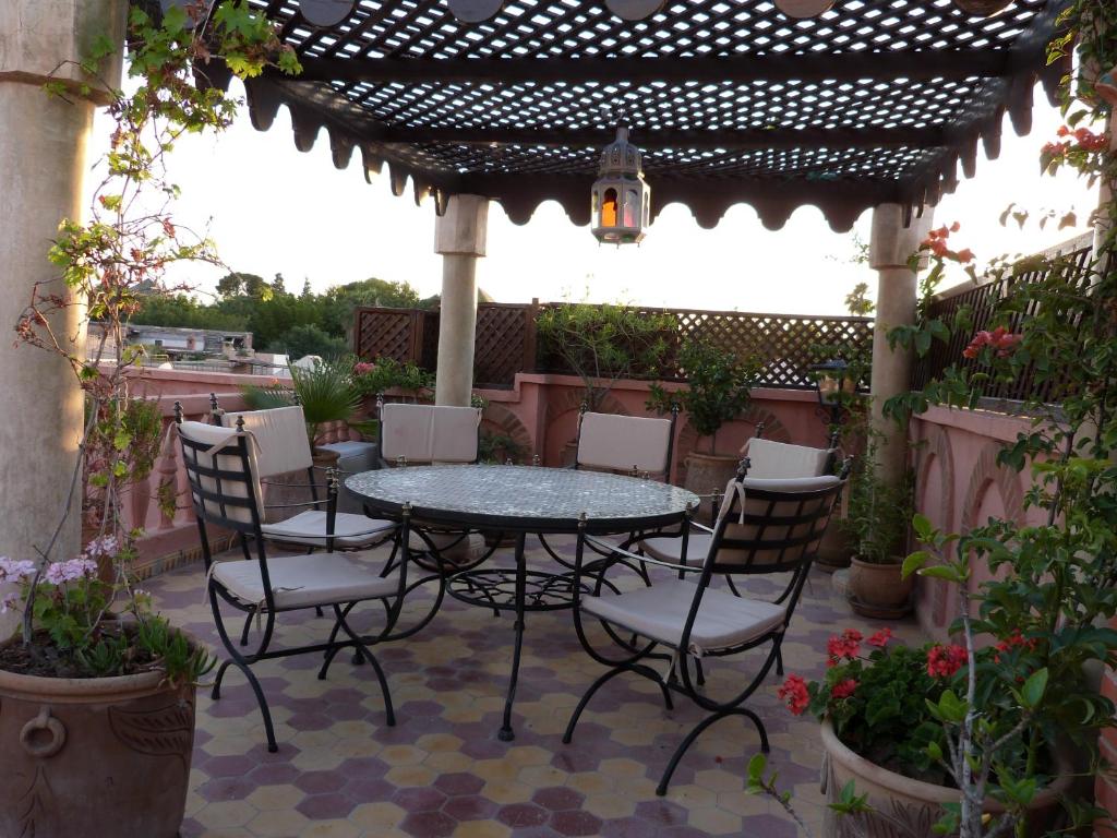 un patio avec une table et des chaises sous une pergola dans l'établissement Riad Habib, à Marrakech