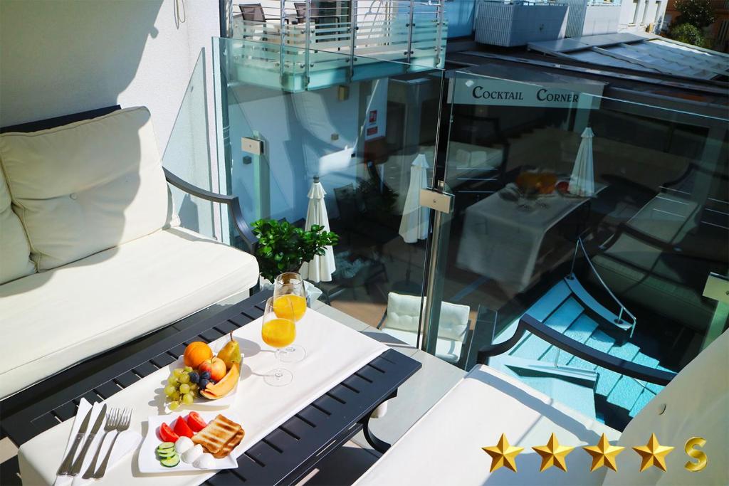 une table avec de la nourriture et des boissons sur un balcon dans l'établissement Hotel Rossini 4S, à Lignano Sabbiadoro