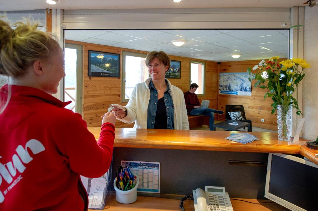 une femme debout à un comptoir dans un bureau dans l'établissement Résidence Capfun Couleurs Soleil, Oz en Oisans, à Oz