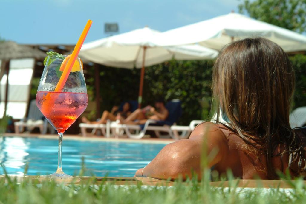 une femme qui se couche à côté d'une piscine avec un verre dans l'établissement Andrea Doria Hotel, à Marina di Ragusa