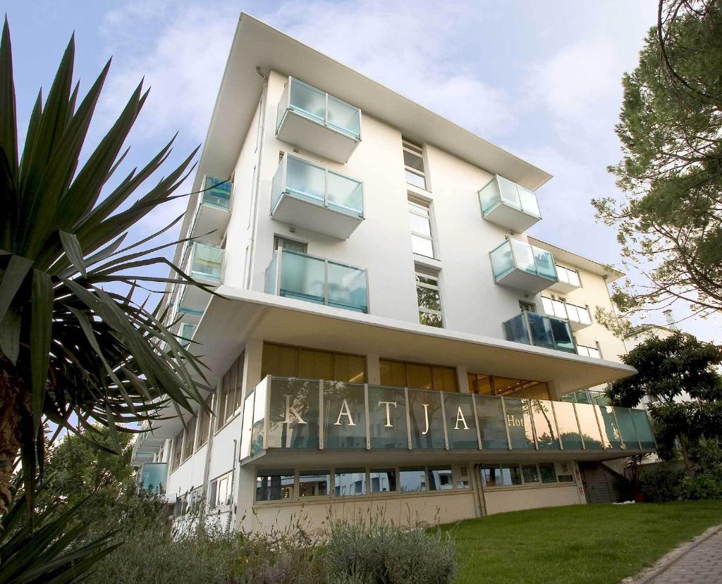 un grand bâtiment blanc avec des balcons sur le côté dans l'établissement Hotel Katja, à Bibione