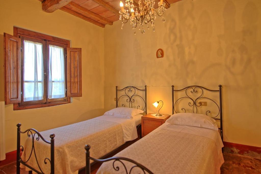 - 2 lits dans une chambre dotée d'un lustre dans l'établissement Agriturismo Podere Delle Querci, à Castiglion Fiorentino