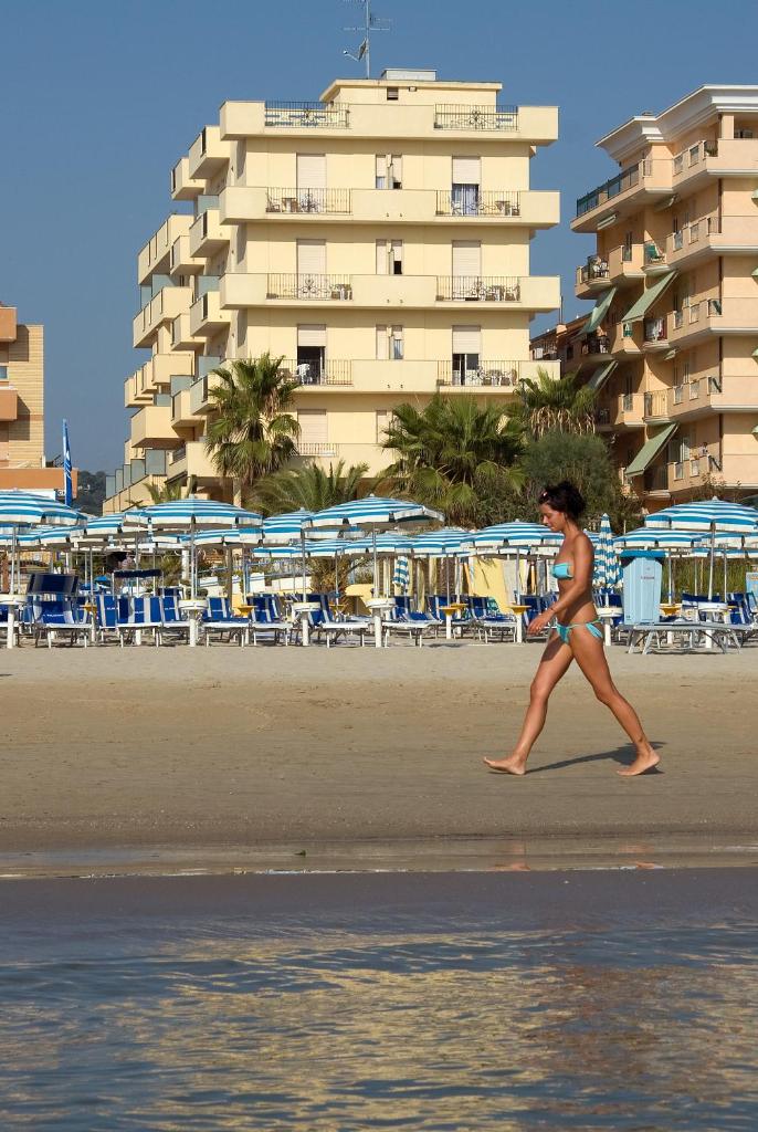 une femme se promenant sur la plage près d'un hôtel dans l'établissement Hotel Bahia, à San Benedetto del Tronto