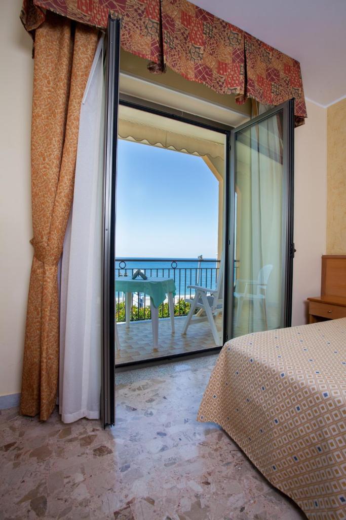une chambre avec une grande porte en verre menant à un balcon dans l'établissement Hotel La Tonnara, à Amantea 43 autres photos
