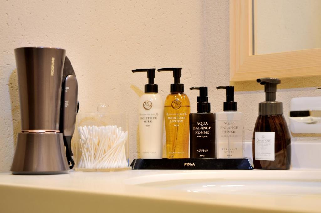 - un comptoir de salle de bains avec des bouteilles de savon sur un lavabo dans l'établissement Oyado Yukizumi, à Kusatsu