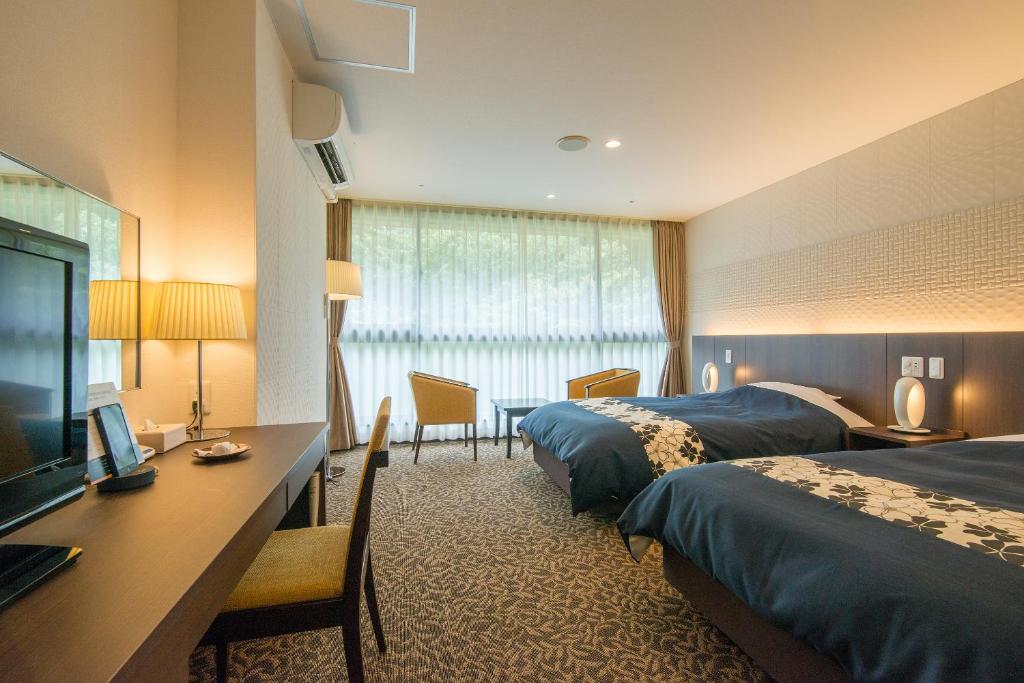 une chambre d'hôtel avec deux lits et une télévision à écran plat dans l'établissement New Welcity Yugawara, à Atami