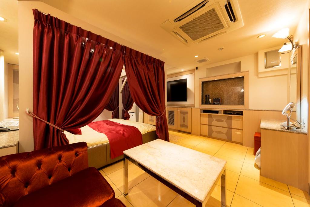 une chambre avec un lit, un canapé et une télévision dans l'établissement Hotel Luna Ikeda (Adult Only), à Ikeda