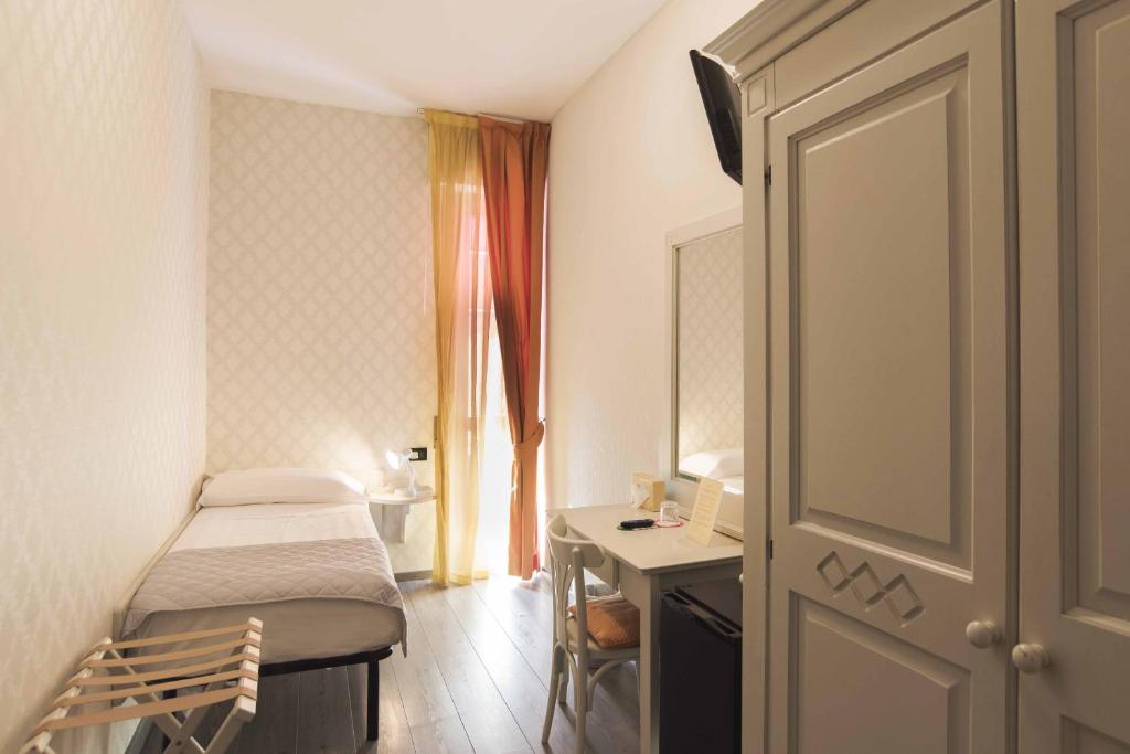 une petite chambre avec un lit et un bureau dans l'établissement Hotel Marisa, à Albenga