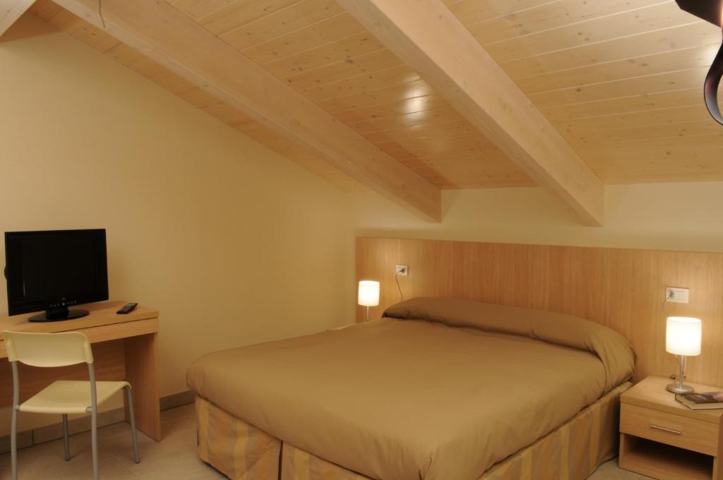 une chambre avec un lit et un bureau avec une télévision dans l'établissement Residence Belmare, à Rimini