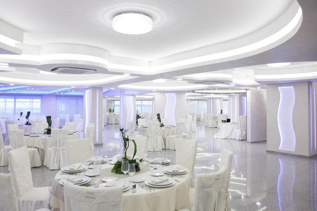 une salle de banquet avec des tables blanches et des chaises blanches dans l'établissement Hotel Melissa, à Torre Melissa