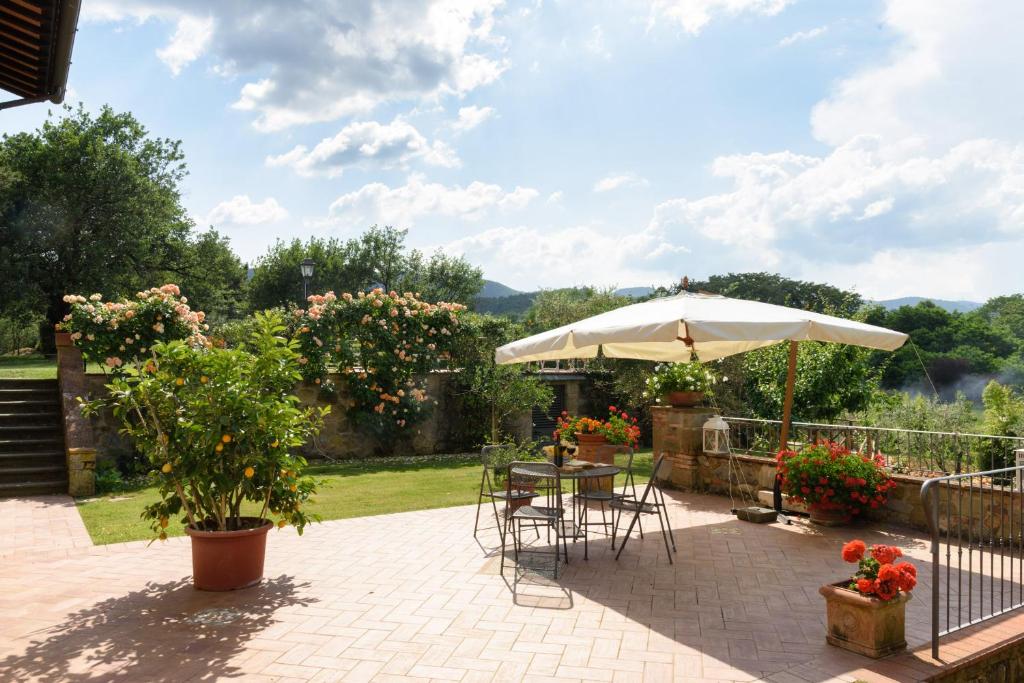 un patio avec un parasol, une table et des chaises dans l'établissement La Villa di Primo, à Cavriglia