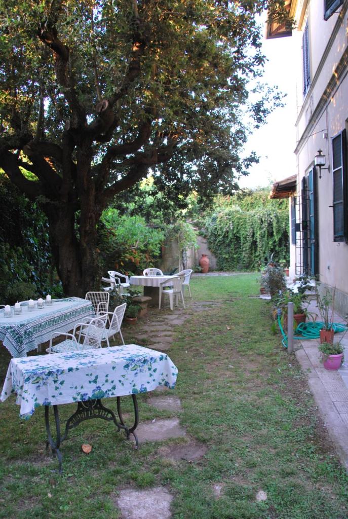 un groupe de tables et de chaises sous un arbre dans l'établissement Villa Carola, à San Giuliano Terme