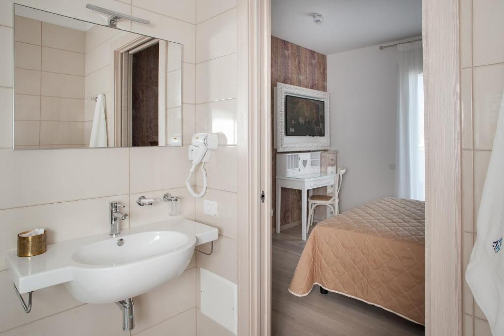 - une salle de bains blanche pourvue d'un lavabo et d'un lit dans l'établissement Hotel Albatros 3 Stelle Superior, à Lido di Jesolo