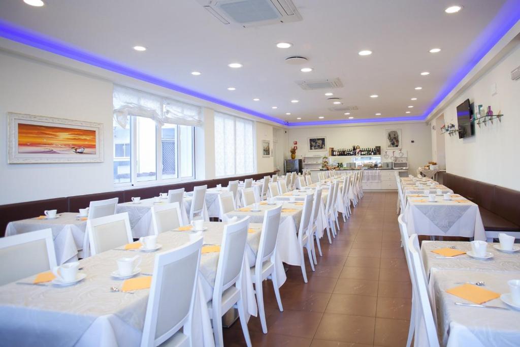 une salle à manger avec des tables blanches et des chaises blanches dans l'établissement Hotel Albatros 3 Stelle Superior, à Lido di Jesolo