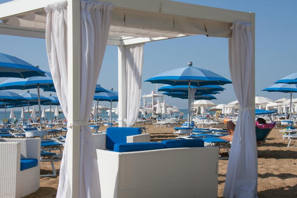 - une plage avec des chaises et des parasols bleus dans l'établissement Hotel Albatros 3 Stelle Superior, à Lido di Jesolo