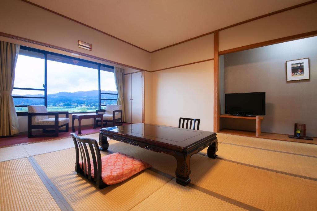 un salon avec une table et une grande fenêtre dans l'établissement Yufuin Sansuikan, à Yufu